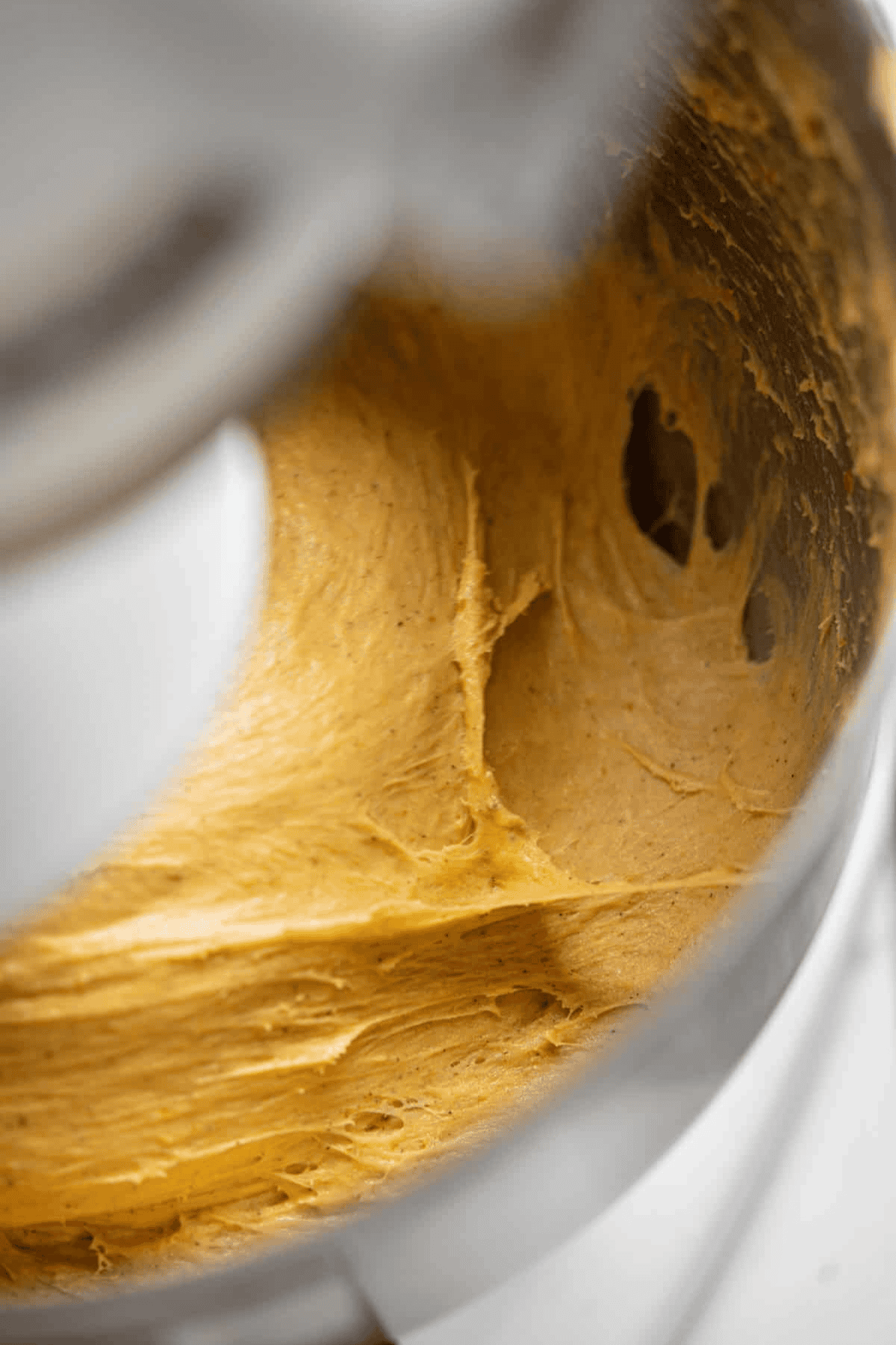 Close-up of creamy pumpkin babka cookie dough being mixed in a metal stand mixer bowl.