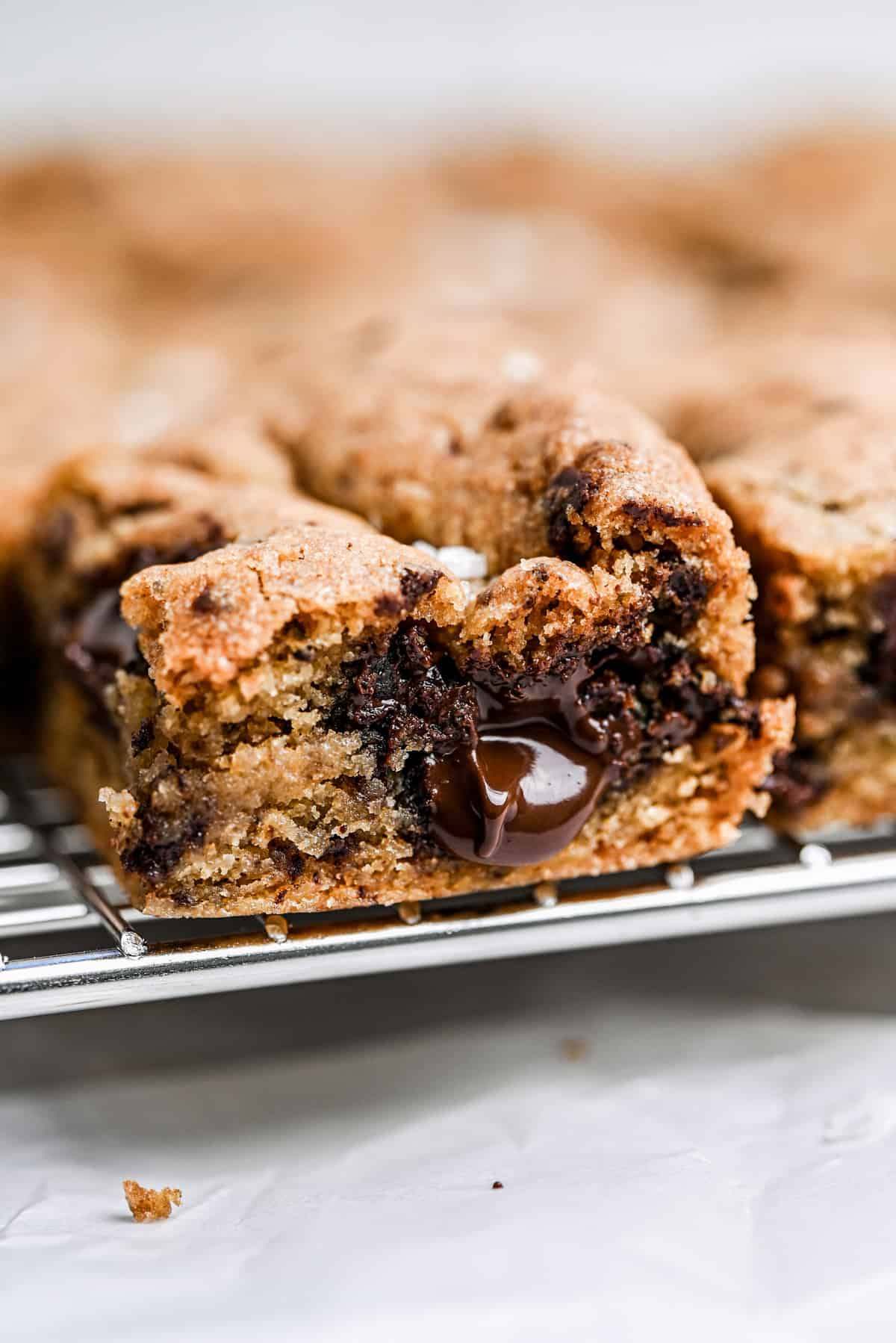 A close-up of a gooey sourdough cookie bar with melted chocolate chunks, resting on a cooling rack.