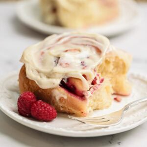 A white chocolate raspberry roll on plate.