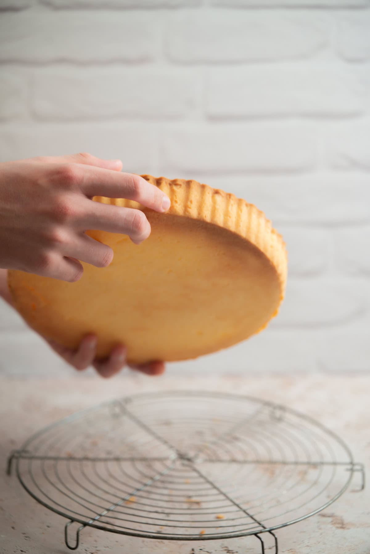 A person holds a plain, round pate sucree base.