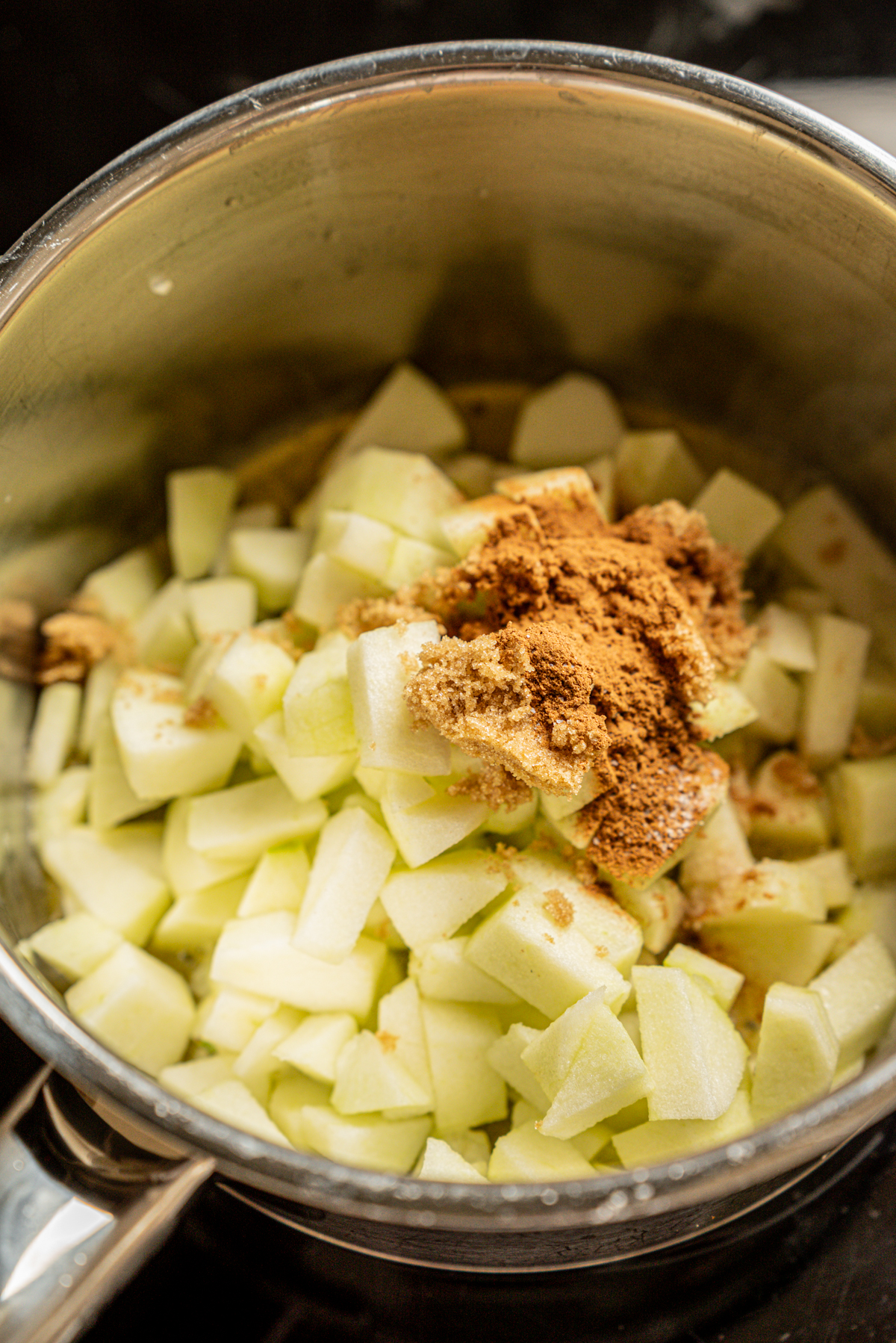 Diced green apples in a metal pot, topped with brown sugar and ground cinnamon, ready to be cooked—perfect for filling Strawberry Cream Cheese Danish Pastries.