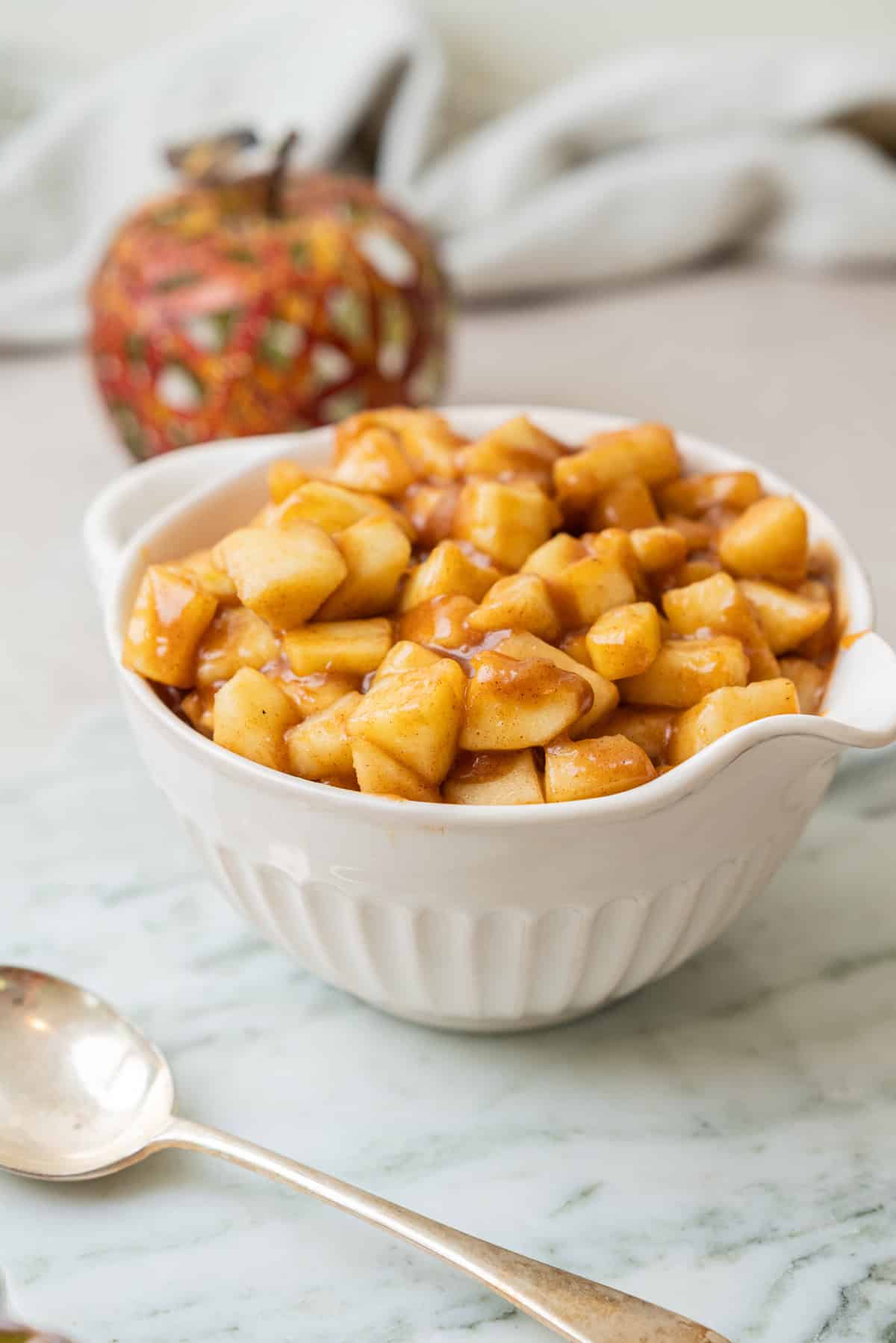 A white bowl filled with cooked, diced apples in a cinnamon glaze.