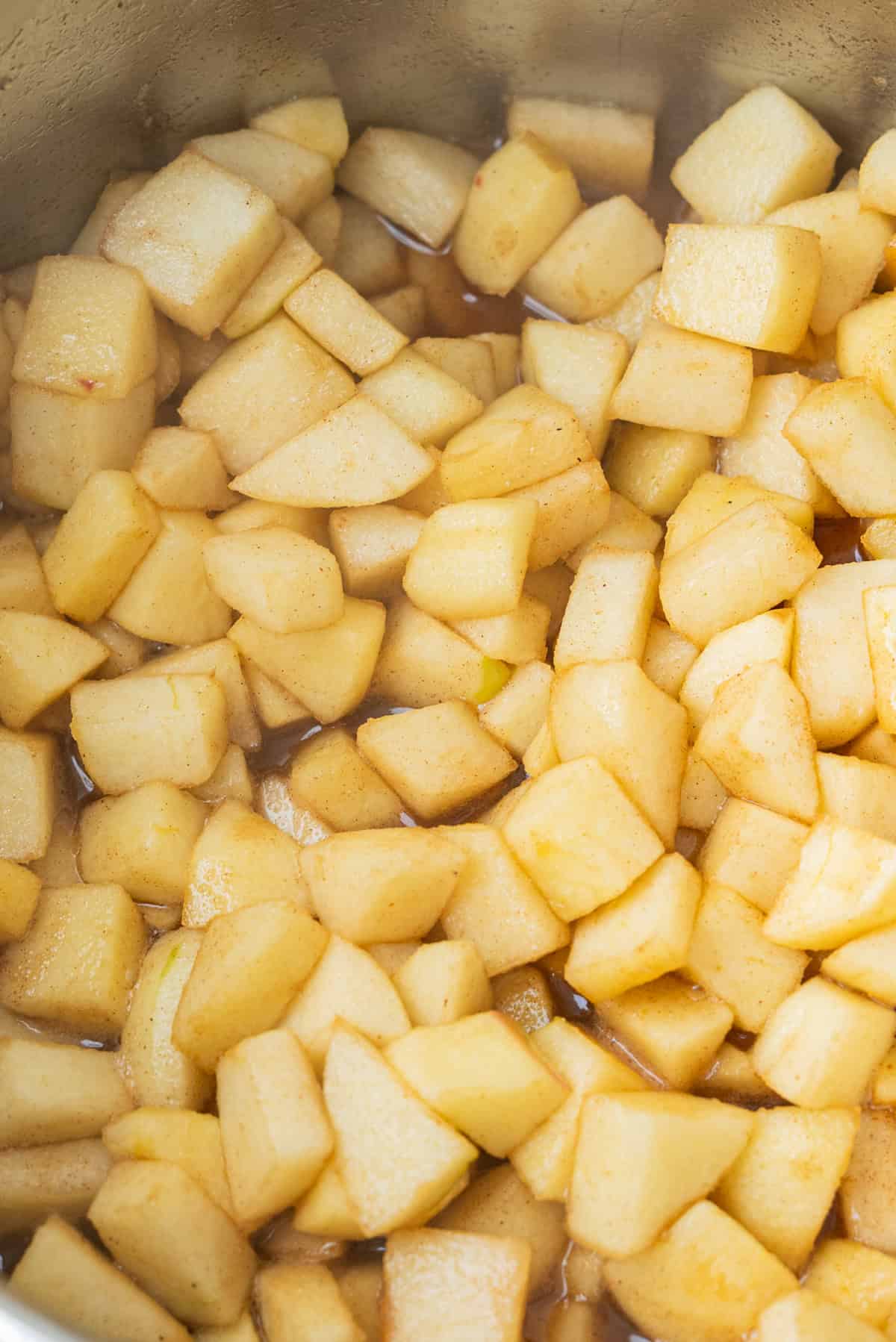Diced apples cooking in a pot with cinnamon.